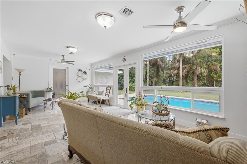Bright living space featuring large windows and glass doors overlooking a pool area