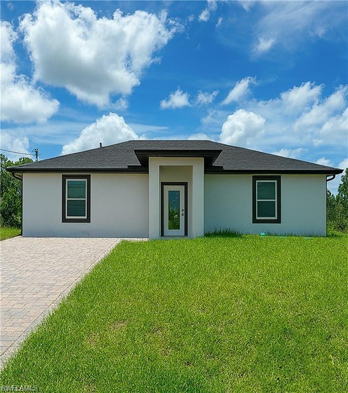 Contemporary stucco exterior with a dark shingle roof, contrasting dark-framed windows, and a glass-paneled entry door