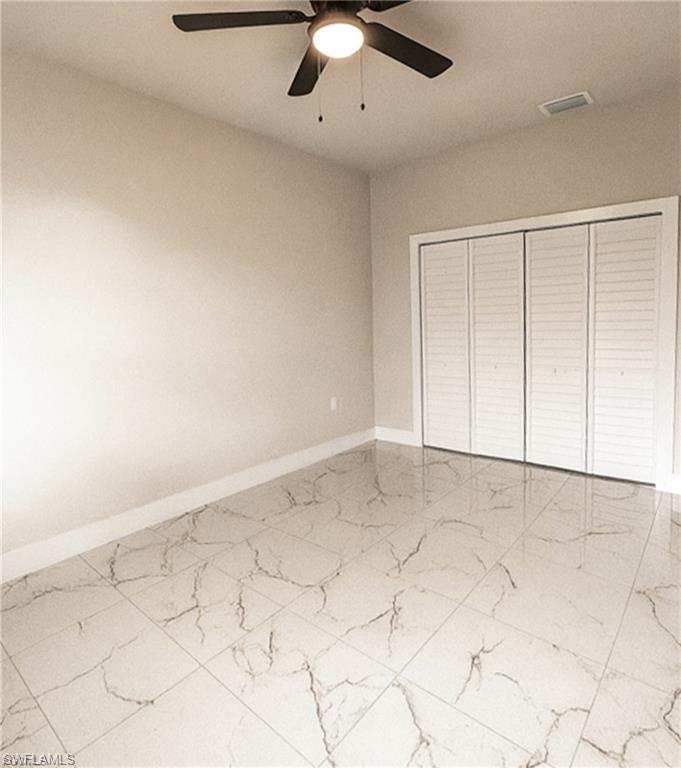 Room featuring large format marble-look tile flooring, louvered bi-fold closet doors, a ceiling fan with integrated lighting, and neutral wall tones