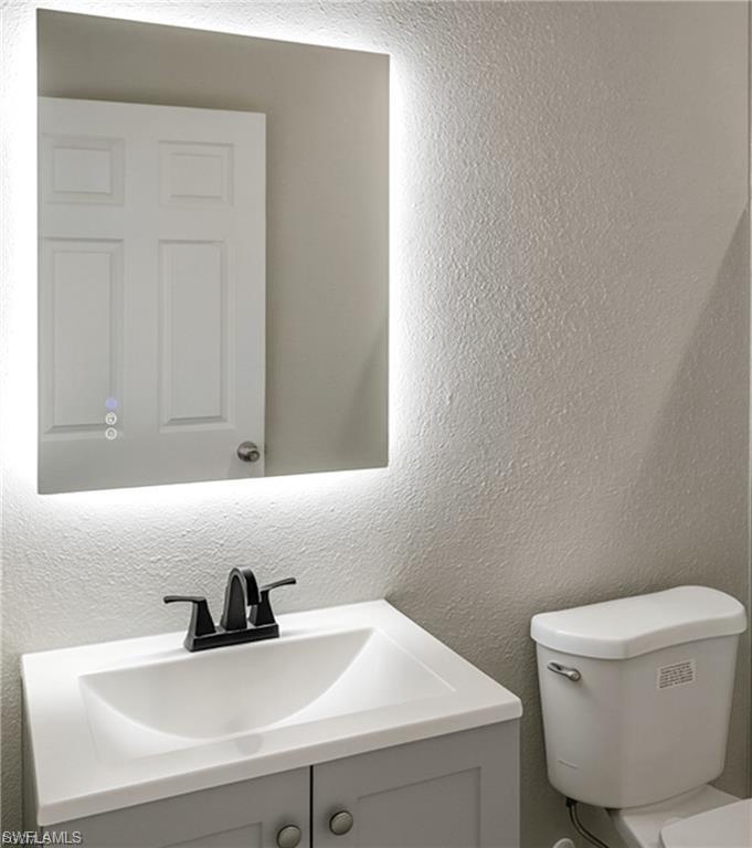 Bathroom vanity featuring an integrated sink, matte black faucet, and a wall-mounted illuminated mirror