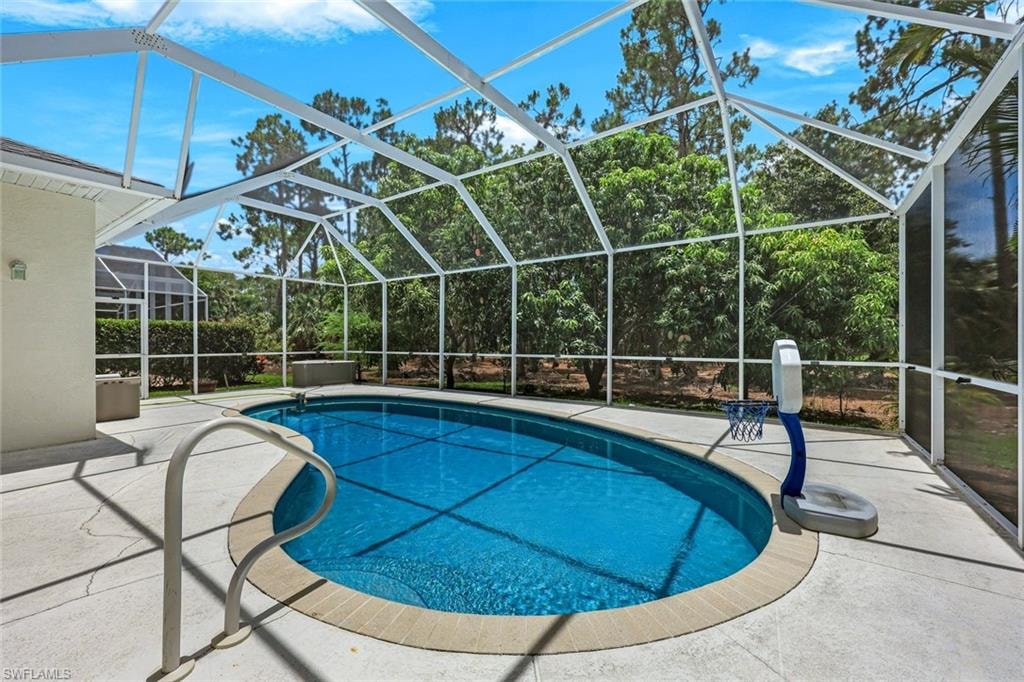 Swimming pool featuring a patio area and glass enclosure
