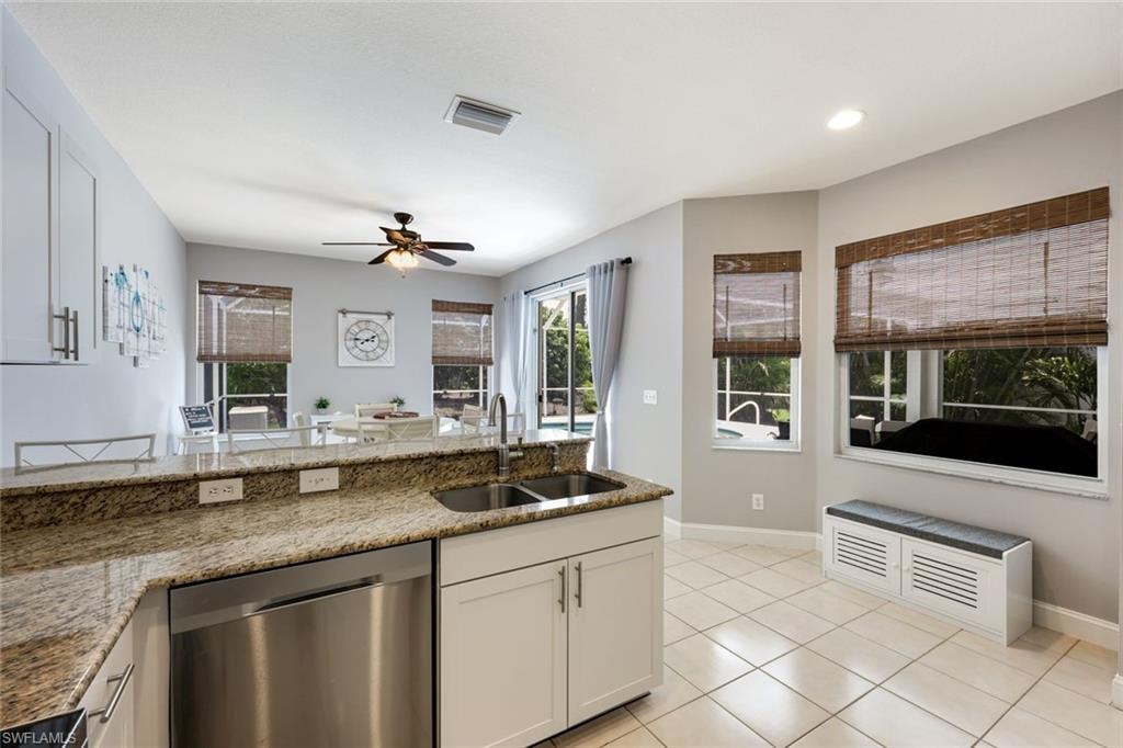 Kitchen featuring dishwasher, a ceiling fan, light tile patterned floors, stone counters, and recessed lighting