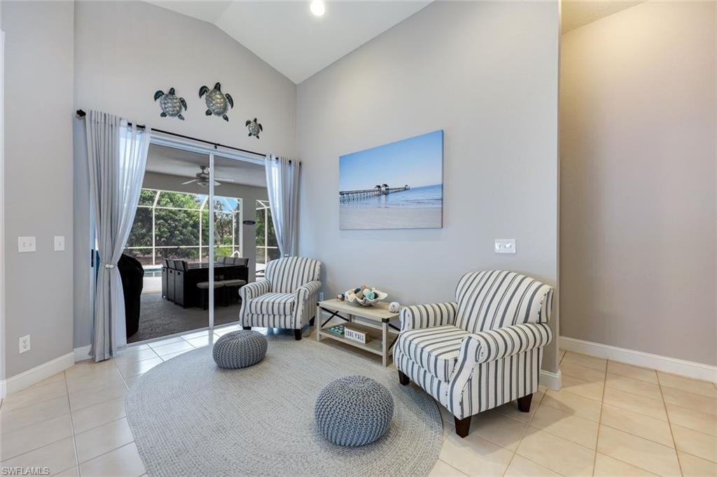 Sitting room with tile patterned flooring, ceiling fan, and high vaulted ceiling