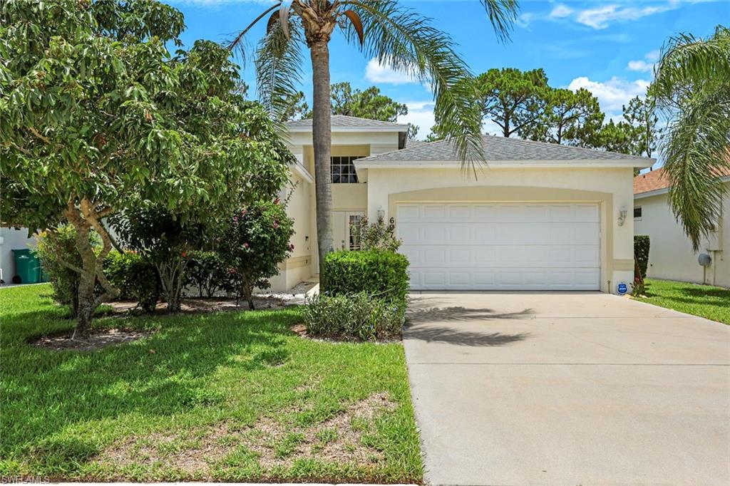View of front facade featuring a garage, concrete driveway, stucco siding, and a front lawn