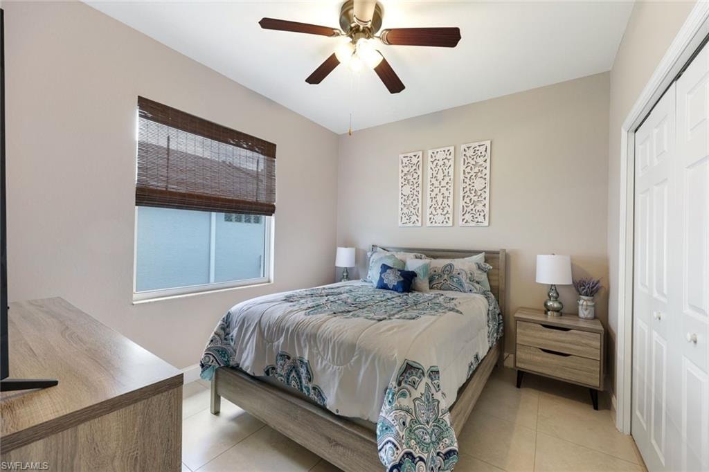 Bedroom with light tile patterned flooring, a closet, and a ceiling fan