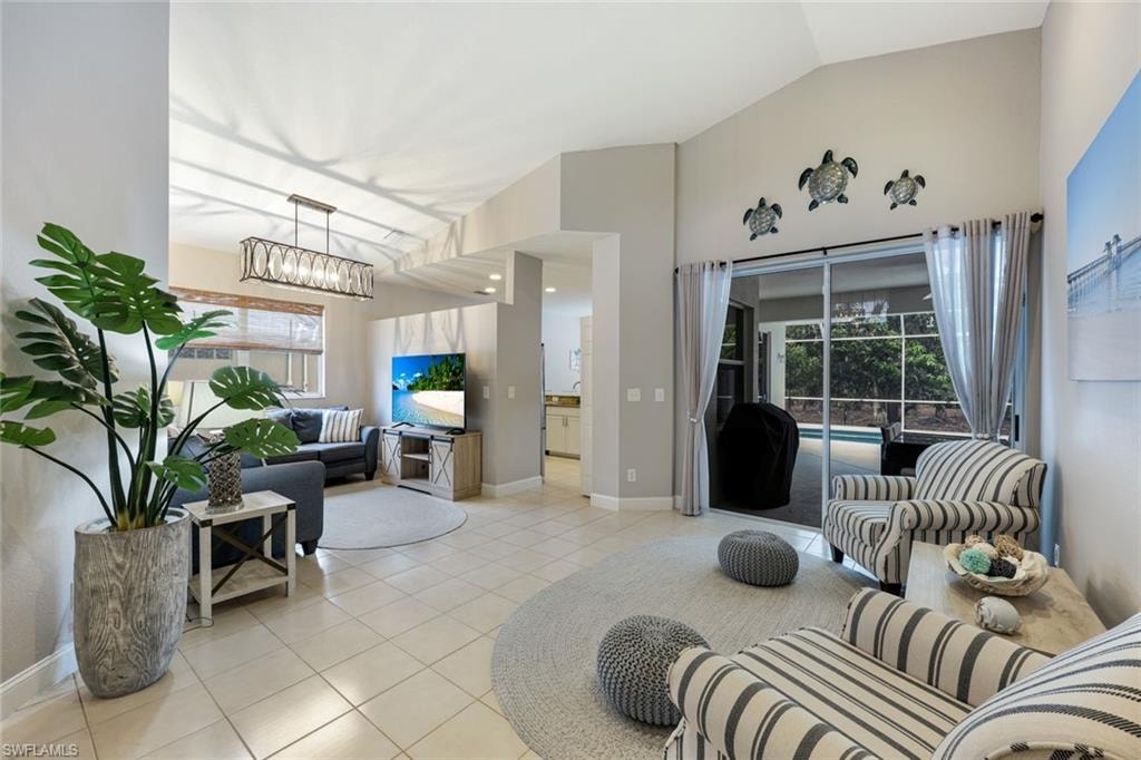 Living area with light tile patterned floors, lofted ceiling, plenty of natural light, and a chandelier