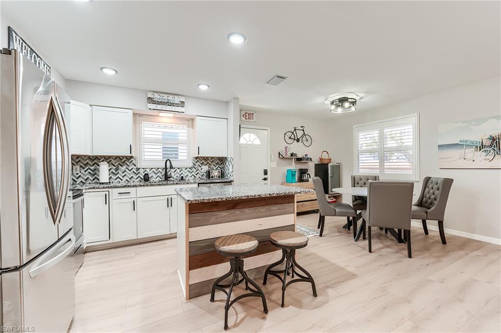 2nd Level Kitchen featuring appliances with stainless steel finishes, light stone countertops, decorative backsplash, white cabinets, and recessed lighting- Virtually Edited Image