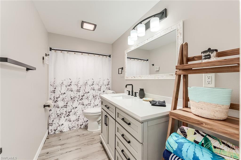 1st Floor Full bathroom with curtained shower, vanity, and light wood-style flooring- Virtually Edited Image