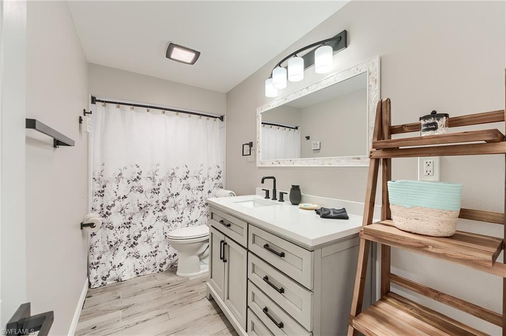 1st Floor Bathroom featuring a shower with curtain, vanity, and light wood finished floors- Virtually Edited Image