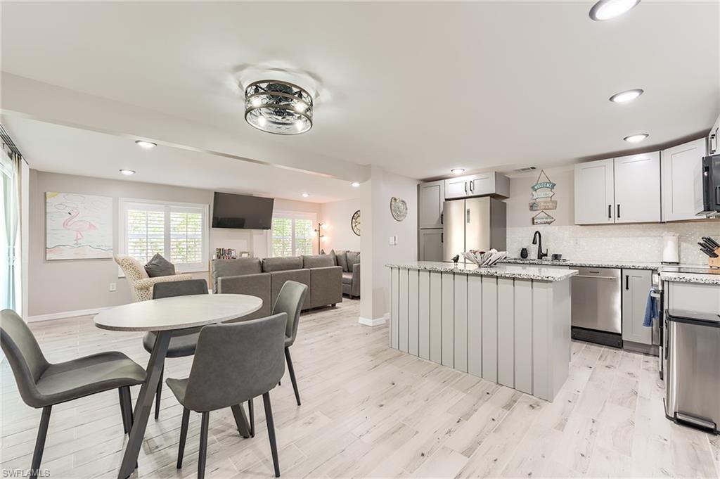 1st Floor Kitchen featuring recessed lighting, a kitchen island, light stone countertops, open floor plan, and tasteful backsplash- Virtually Edited Image