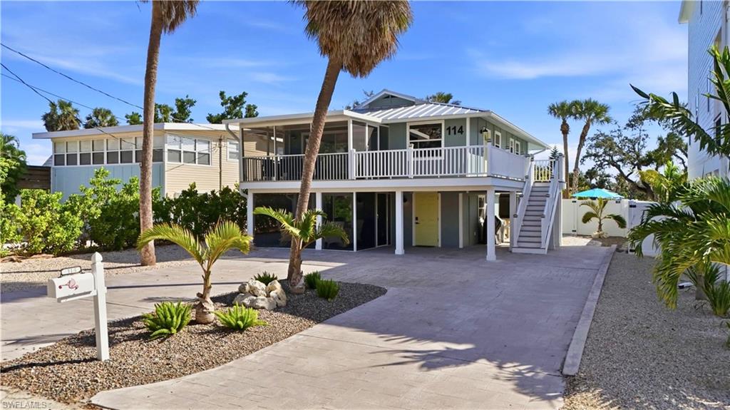 Coastal inspired home featuring a carport, decorative driveway, stairway, and a deck- Virtually Edited Image