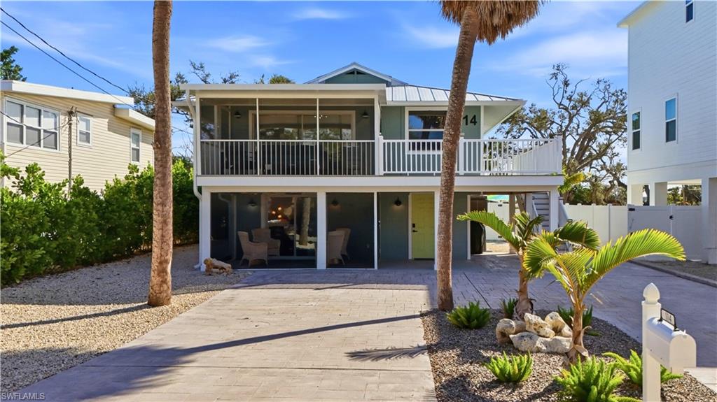 Rear view of property featuring a patio area, decorative driveway, stairs, and a sunroom- Virtually Edited Image