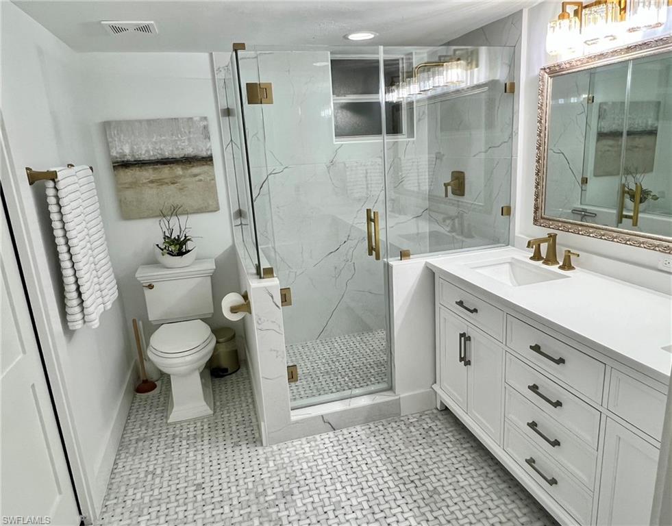 White vanity with an integrated sink, polished brass fixtures, and a framed mirror