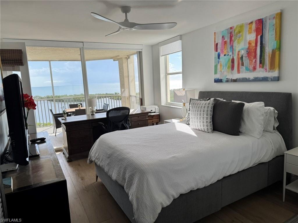 Room featuring floor-to-ceiling glass doors, wood-finish flooring, and a modern ceiling fan