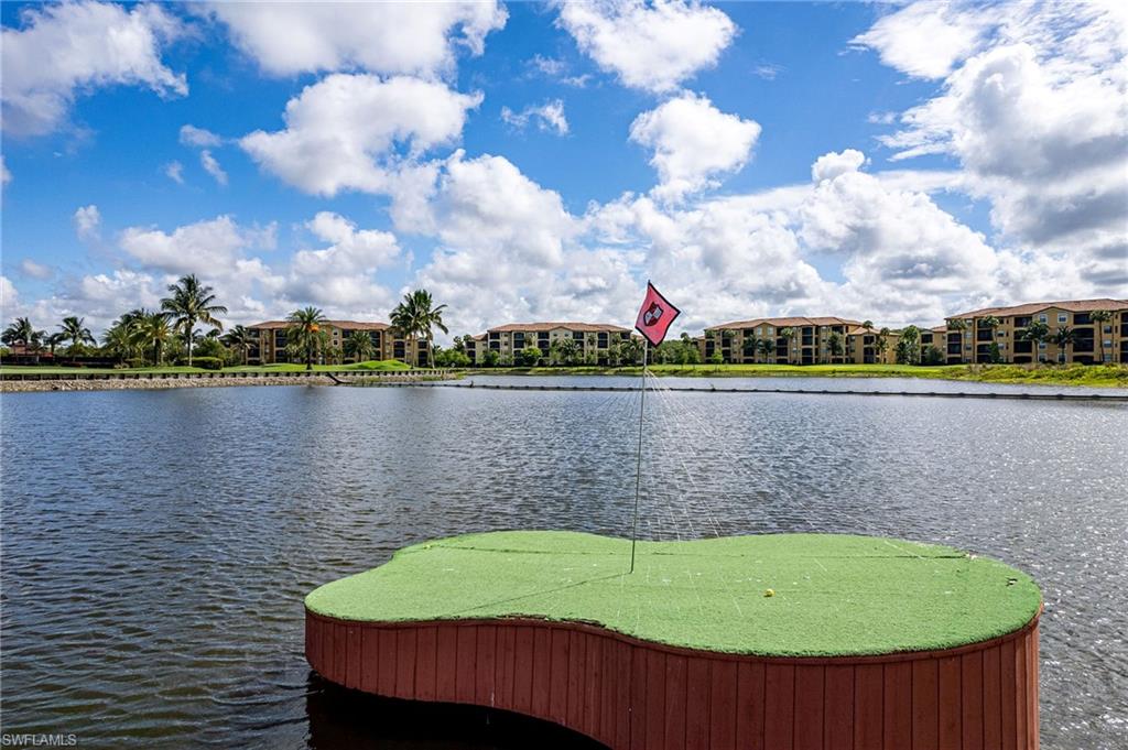 Floating artificial turf green with a red flag, positioned on a lake with a residential backdrop