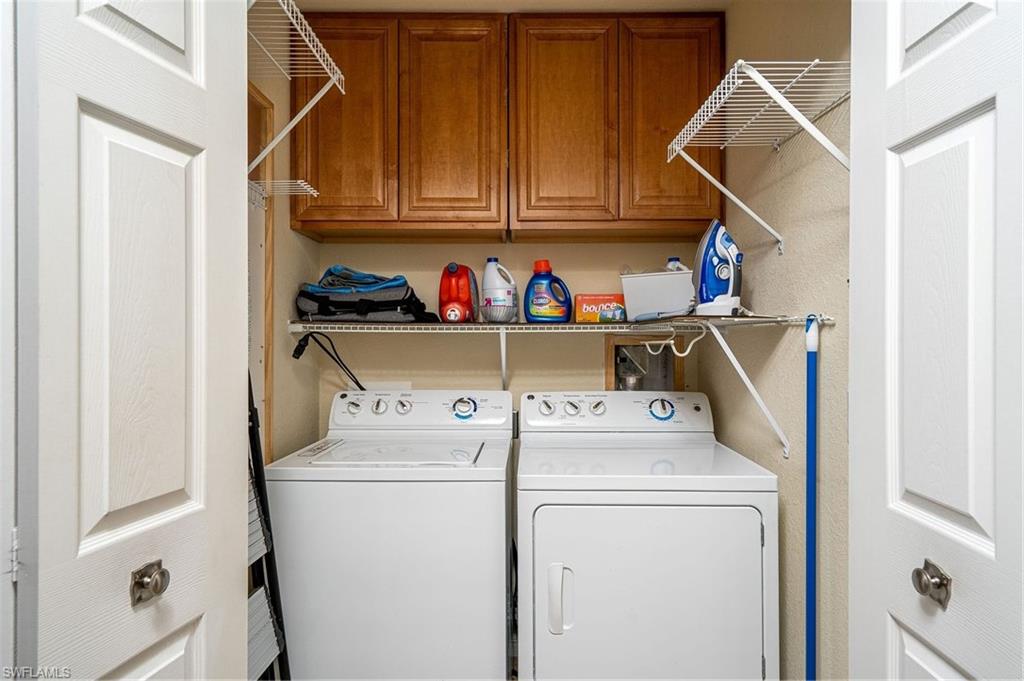 Dedicated laundry area featuring a washer and dryer, wood cabinetry, and wire shelving for storage
