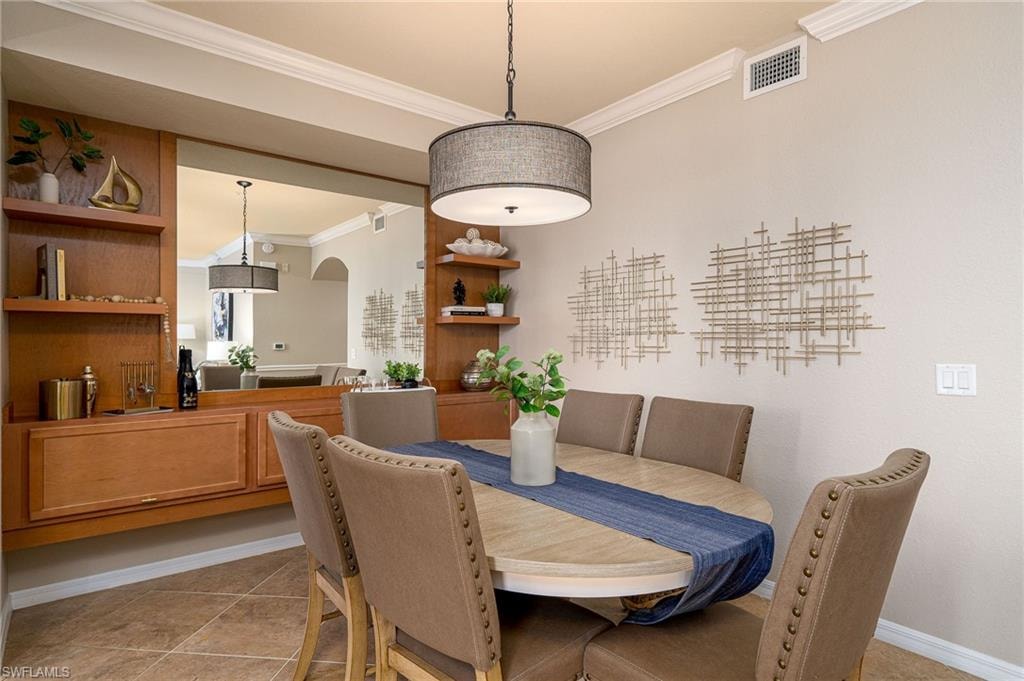 Dining area featuring built-in wood cabinetry with integrated shelving, a large wall mirror, and crown molding