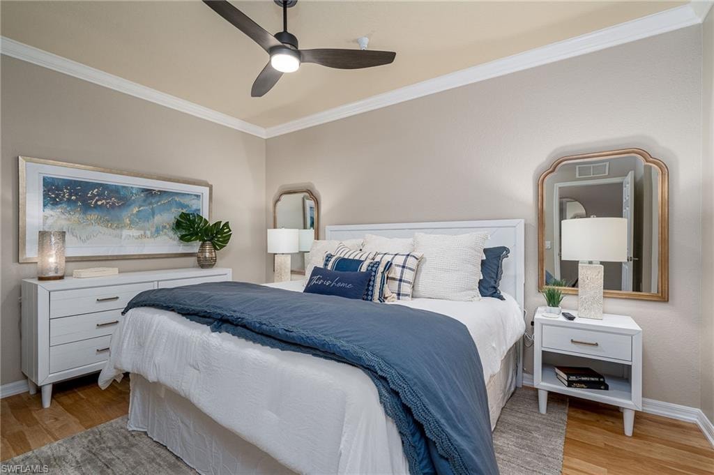 Bedroom featuring wood-finish flooring, crown molding, a ceiling fan with integrated lighting, and neutral wall tones