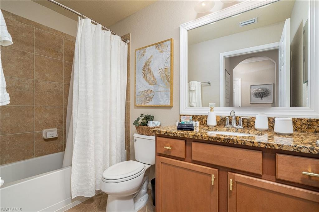 Bathroom featuring a vanity with granite countertop, integrated sink, and wood cabinetry