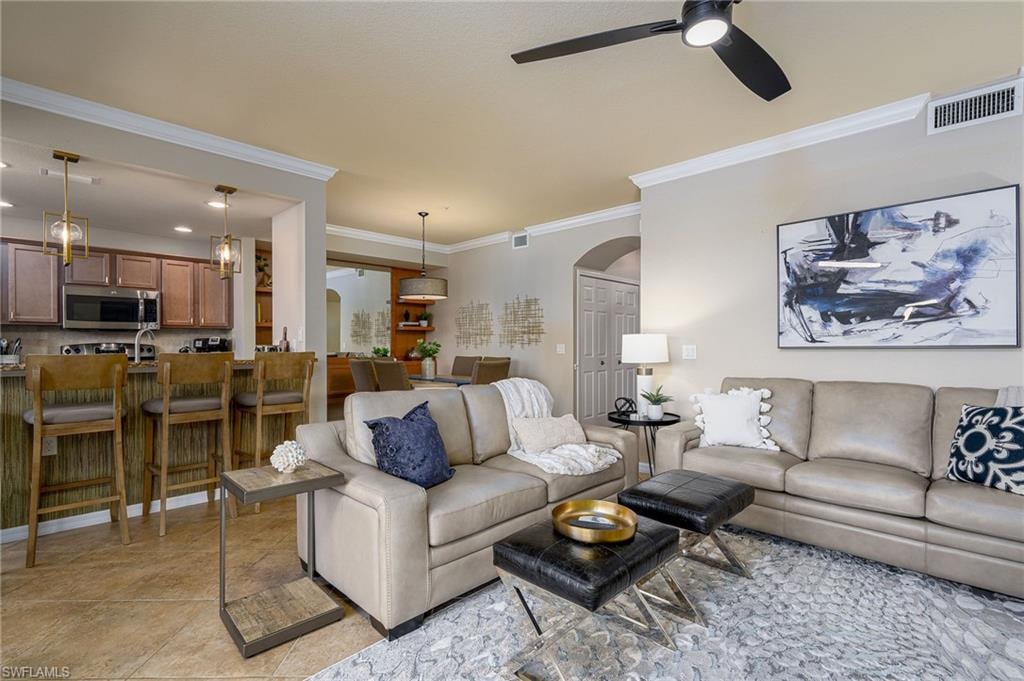 Open-concept living area featuring tile flooring and crown molding