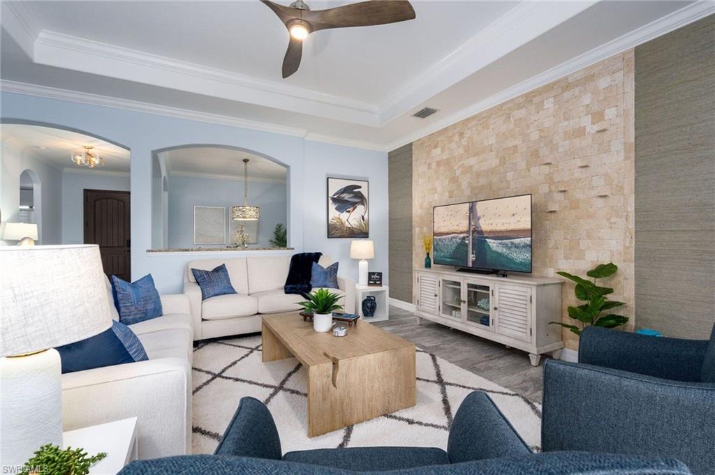 Living area featuring a tray ceiling with a ceiling fan, light blue wall paint, and wood-finish flooring