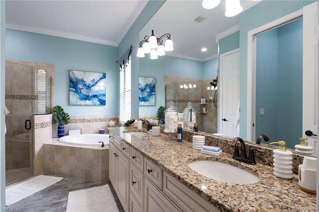 Double vanity with a granite countertop and dual oval sinks, a built-in jetted tub, a tiled walk-in shower with a glass enclosure, and wood-finish cabinetry