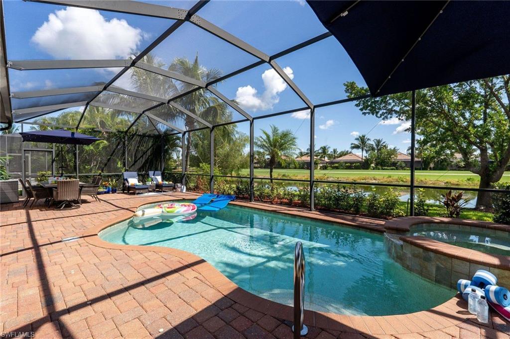Screened outdoor living area featuring a freeform pool, integrated spa, and brick paver patio