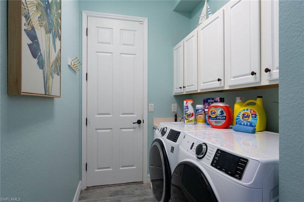 Laundry area featuring white shaker-style cabinetry with dark hardware, a built-in counter, and wood-finish flooring