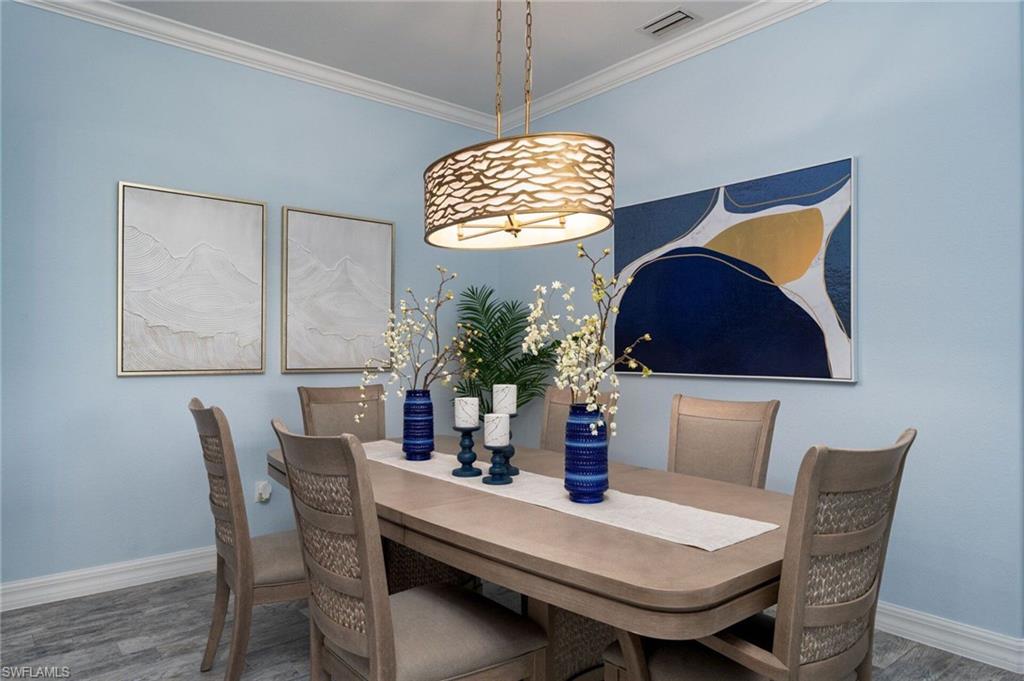 Dining area featuring light blue wall color, crown molding, and wood-finish flooring