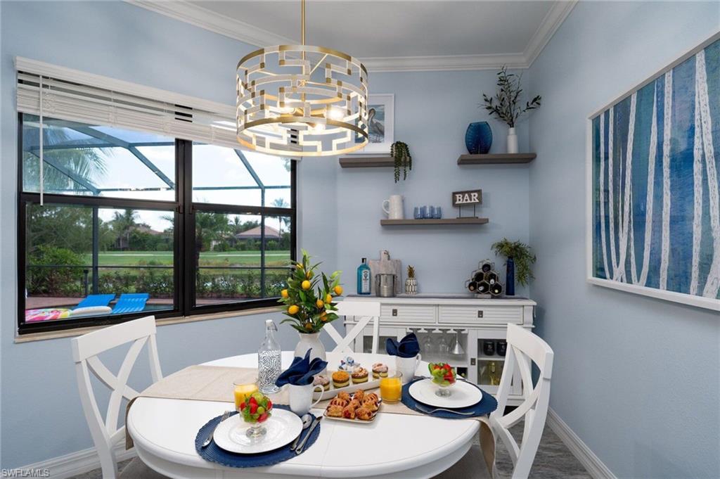 Dining area featuring a contemporary brass chandelier, light blue walls, and a large window overlooking a lush green landscape