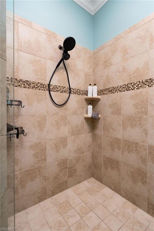 Shower enclosure with light beige wall tiles and a mosaic tile accent band