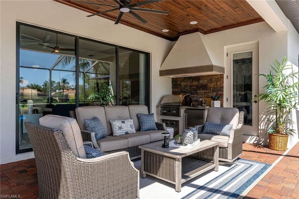Covered outdoor living area featuring a wood-finish tongue-and-groove ceiling, ceiling fan, and brick paver flooring