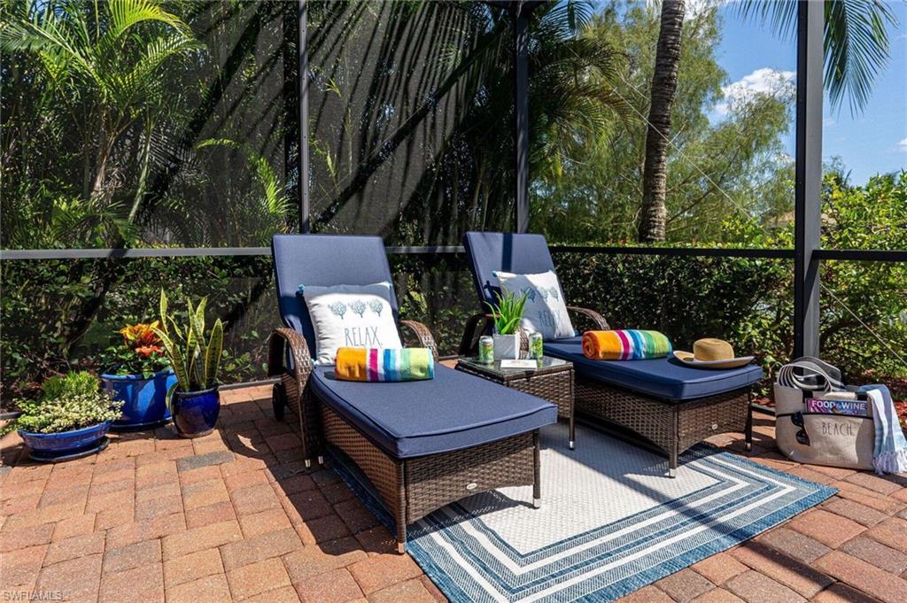 Screened lanai featuring paver flooring and lush tropical landscaping