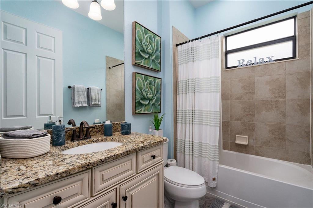 Full bathroom featuring a single vanity with granite countertop, integrated sink, and white cabinetry