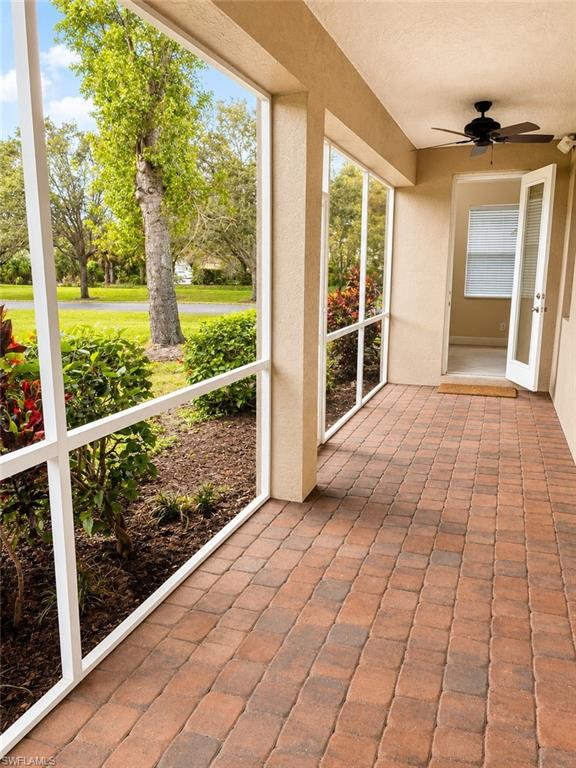 Screened patio featuring paver flooring, a ceiling fan, and direct outdoor access