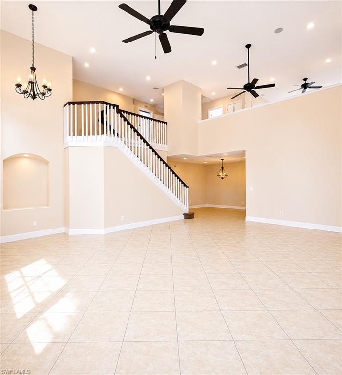 Spacious double-height living area featuring neutral-toned tile flooring, recessed lighting, and multiple ceiling fans