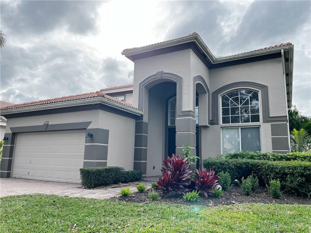 Contemporary stucco exterior featuring an arched entry, a two-car garage, an arched multi-pane window, and a tile roof