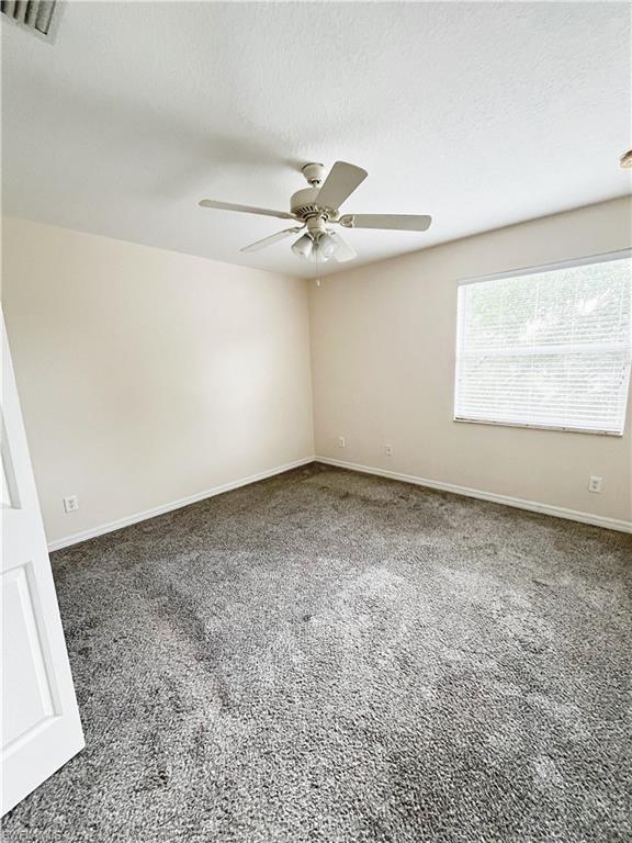 Spacious room featuring neutral wall tones and plush grey carpeting
