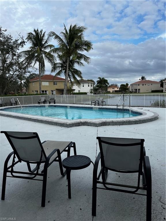 Outdoor swimming pool featuring perimeter fencing, an integrated spa, and a surrounding concrete deck