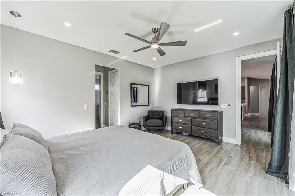 Spacious room featuring light-toned wood-finish tile flooring, a contemporary ceiling fan, recessed lighting, and a crystal pendant light fixture