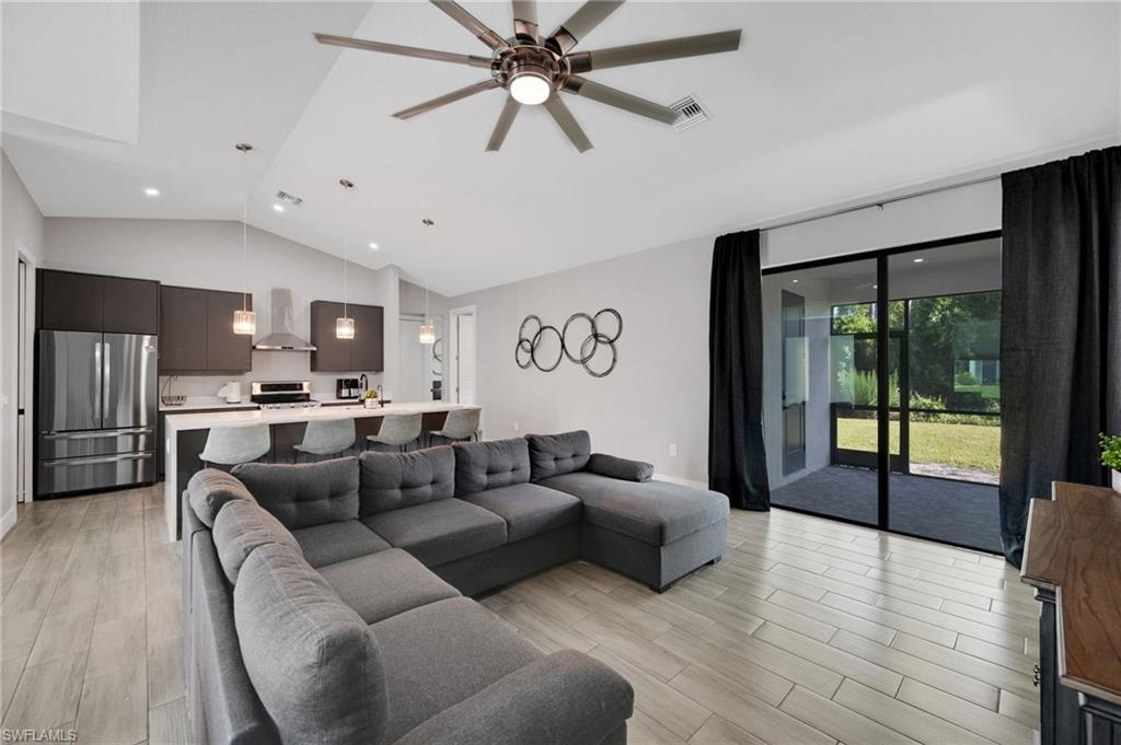 Open-concept living area featuring wood-finish flooring, vaulted ceilings, and recessed lighting