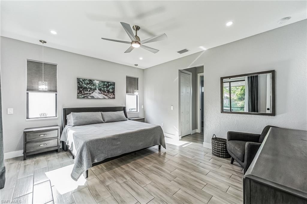 Spacious room featuring light-toned walls, wood-finish tile flooring, recessed lighting, and a ceiling fan
