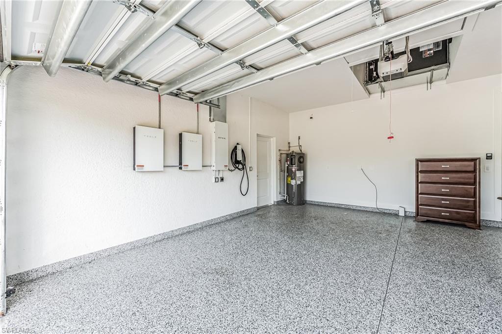 Garage interior featuring a durable epoxy floor, white textured walls, and an overhead garage door