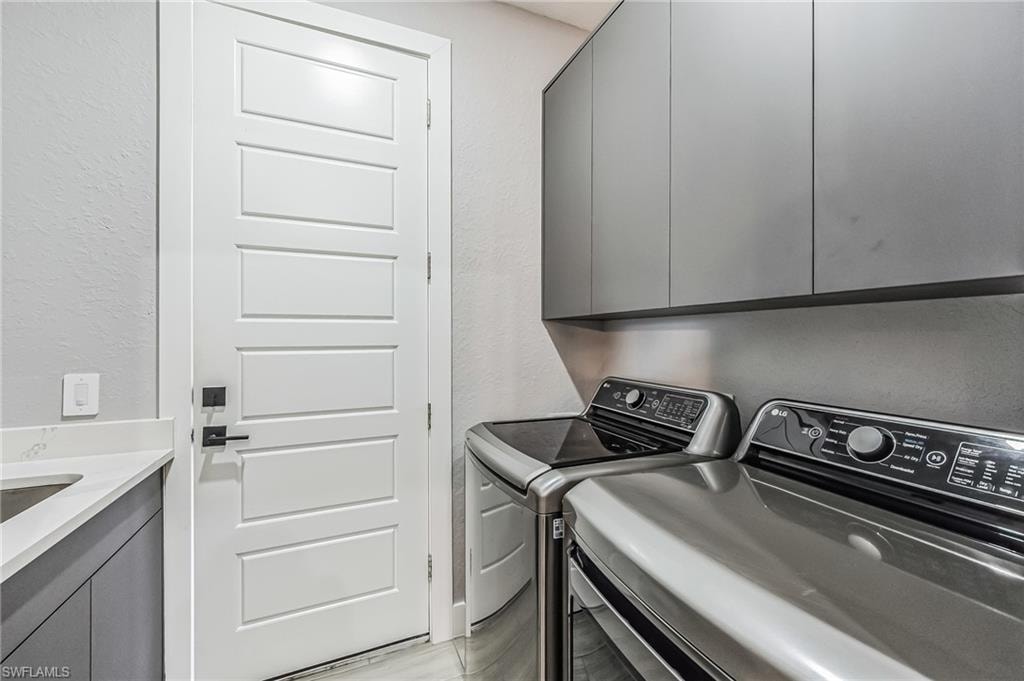 Laundry area featuring a built-in sink, stone countertop, matte gray cabinetry, and white paneled door