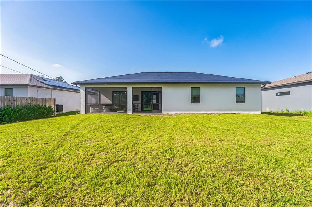 Expansive green lawn with a white stucco exterior featuring a dark-colored roof