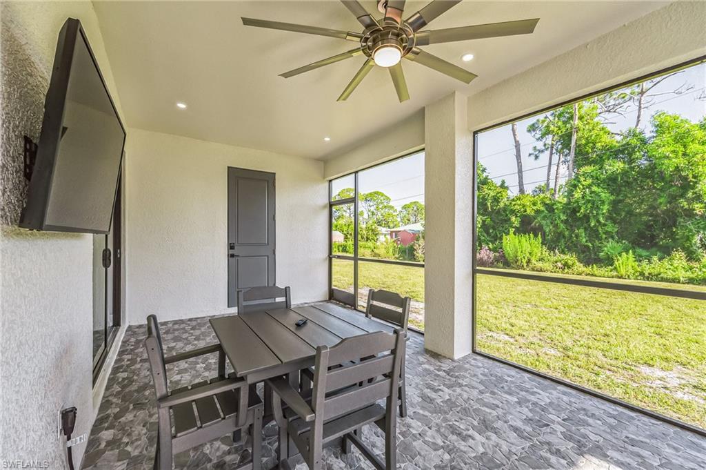 Screened lanai featuring a ceiling fan, recessed lighting, wall-mounted television, tiled flooring, and a solid panel door