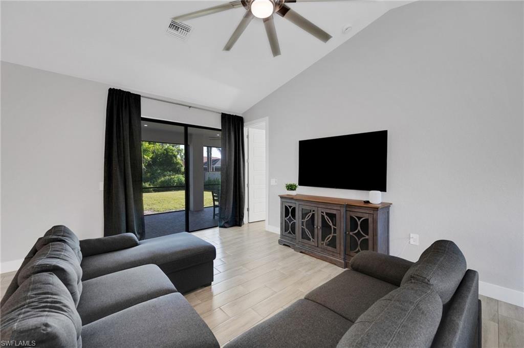 Spacious living area featuring light-toned wood-finish flooring, vaulted ceilings, and a ceiling fan