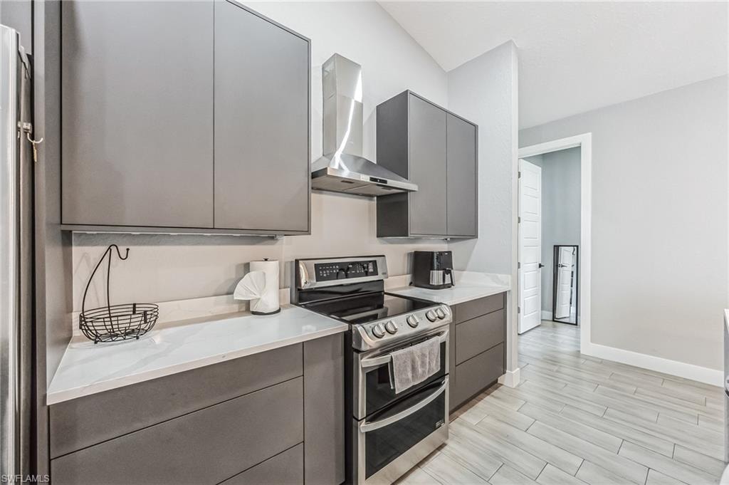 Modern kitchen featuring flat-panel cabinetry, white countertops, stainless steel appliances, and wood-finish tile flooring