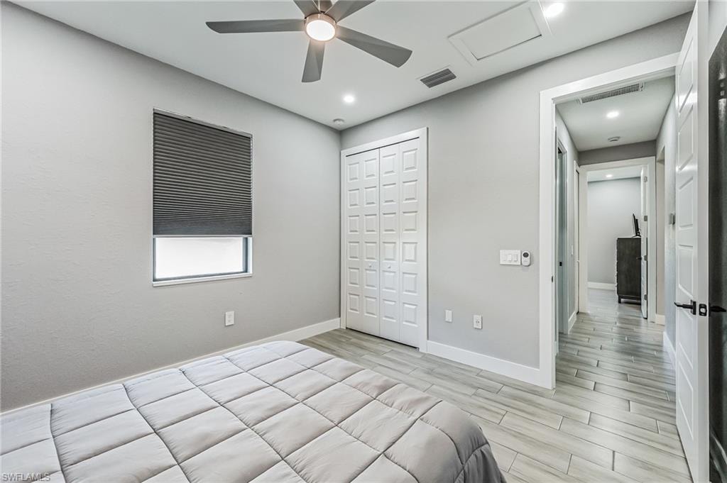 Spacious room featuring light-toned walls, a ceiling fan with integrated lighting, recessed lighting, and elegant wood-finish flooring