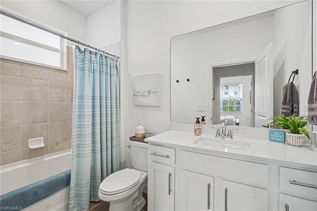 Full bathroom featuring a white vanity with integrated sink, chrome faucet, and quartz-finish countertop